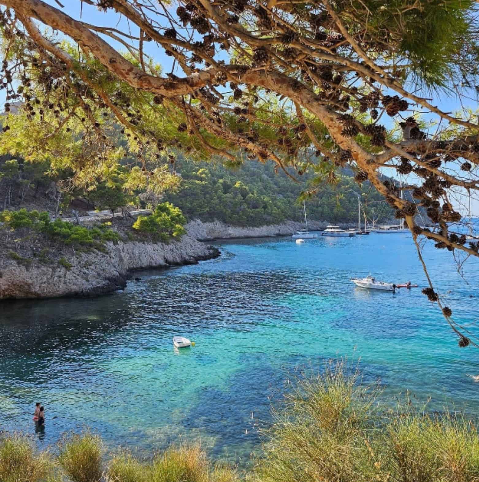 Scenic view of Foki Beach in Fiskardo featuring turquoise waters and boats.