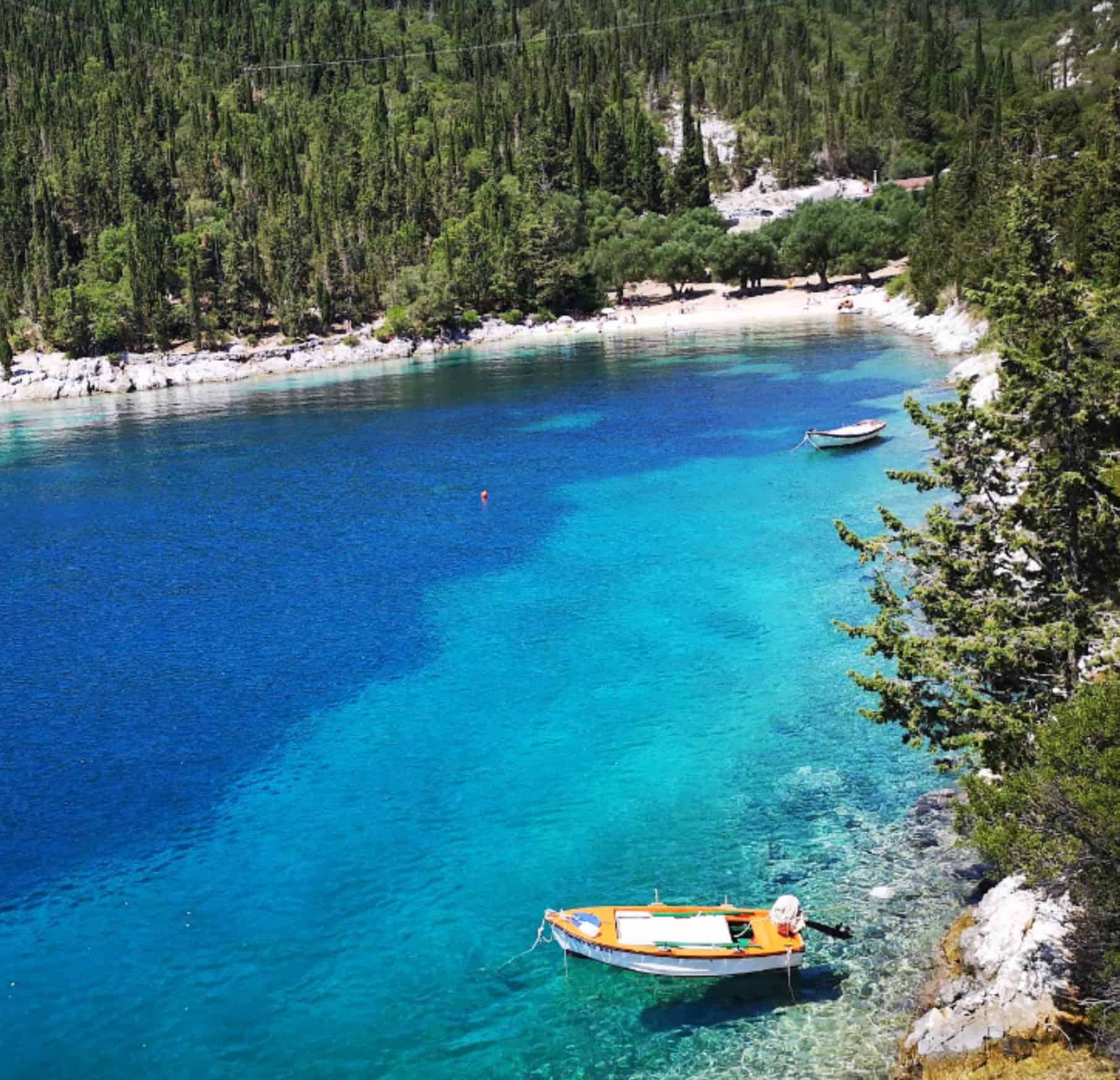 Scenic view of Foki Beach with turquoise waters and boats anchored near the shore.