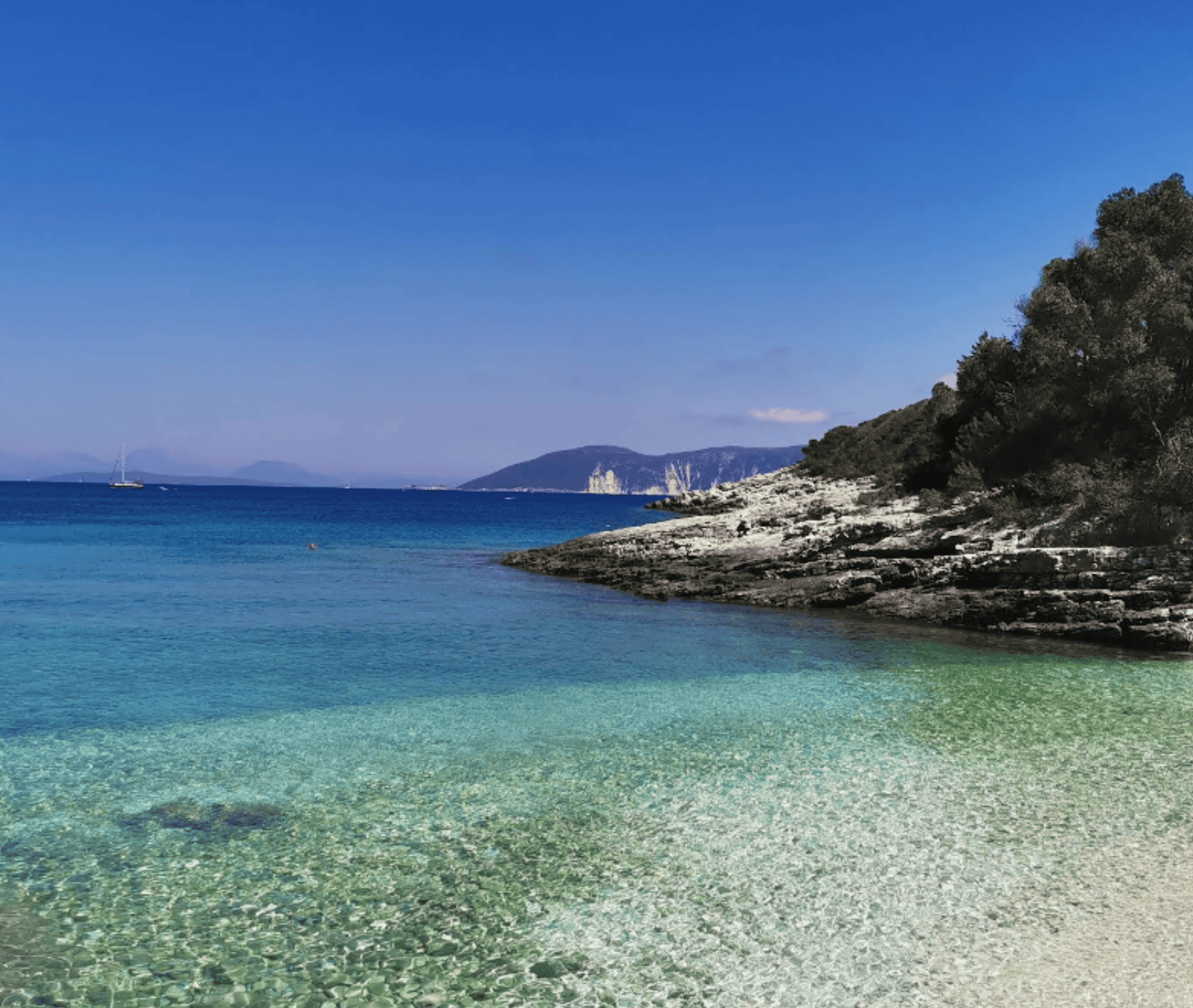 Scenic view of Fiskardo's coastline with clear blue waters and rocky shoreline.