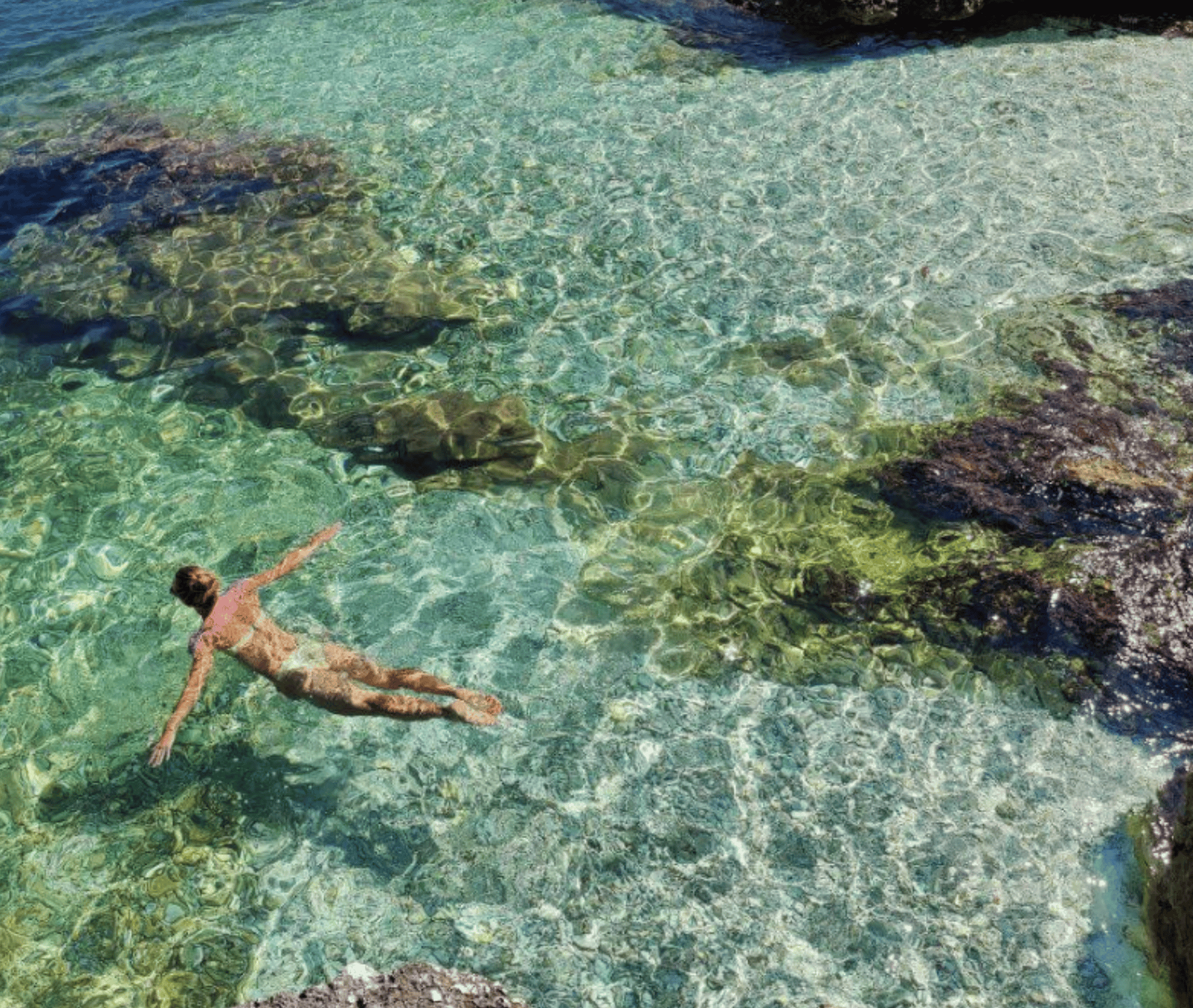 Person relaxing in crystal-clear waters near Fiskardo boat hire.