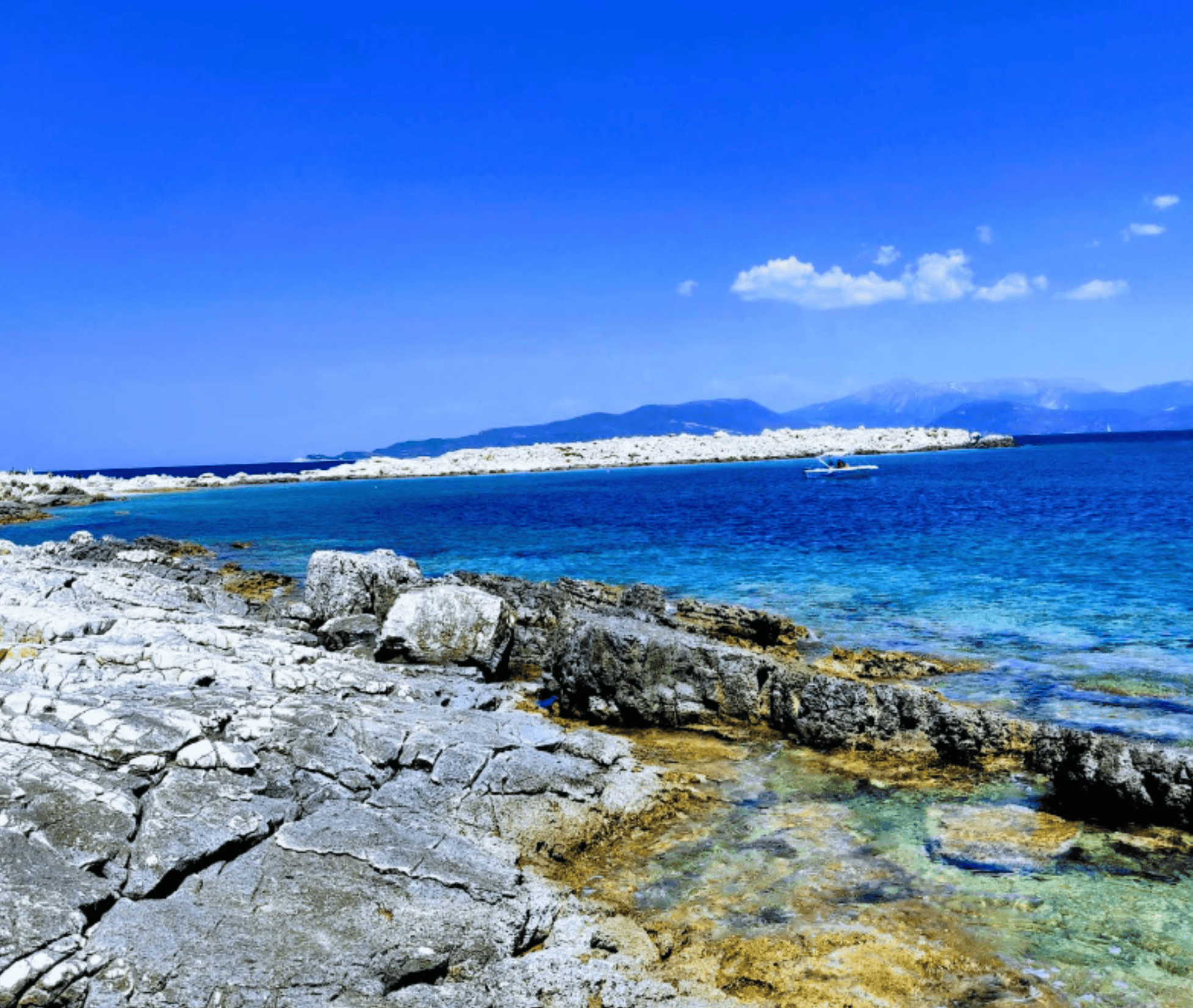 Scenic view of Emplisi Beach with rocky shoreline and clear blue waters.